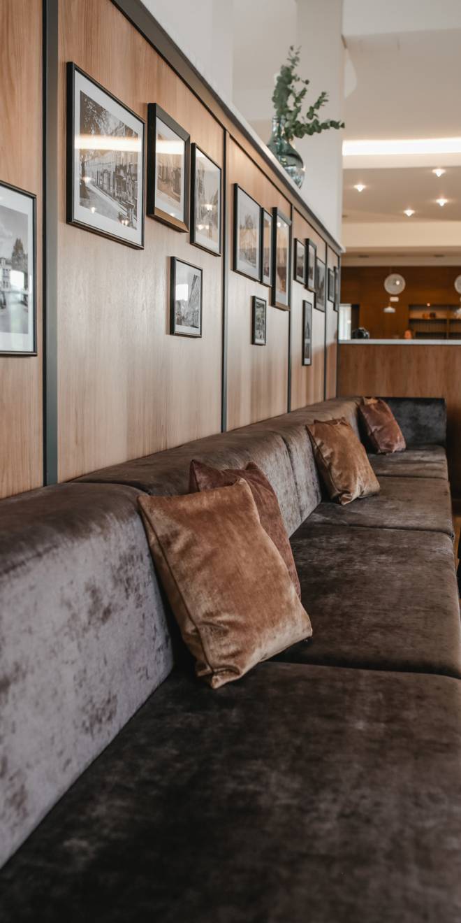 Lobby Innenansicht mit brauner Couch und Bildern an der Holzwand