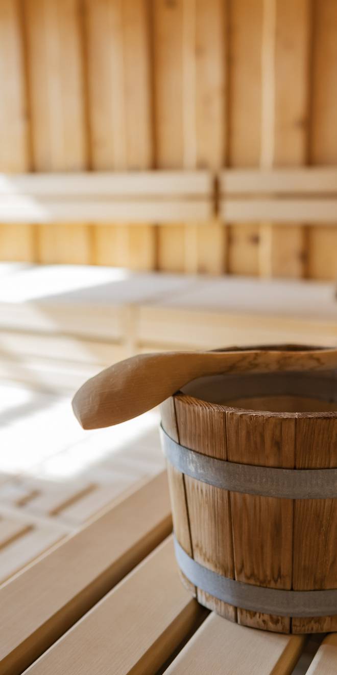 gefüllter Saunaeimer steht auf Holzbank in der Sauna