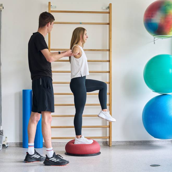 Person führt eine Gleichgewichtsübung mit Anleitung im Fitnessraum des Hotel am Vitalpark aus.