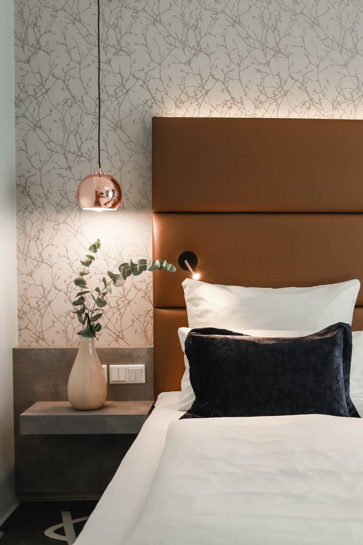 Detailaufnahme Doppelbett mit Blumendeko und Hängelampe