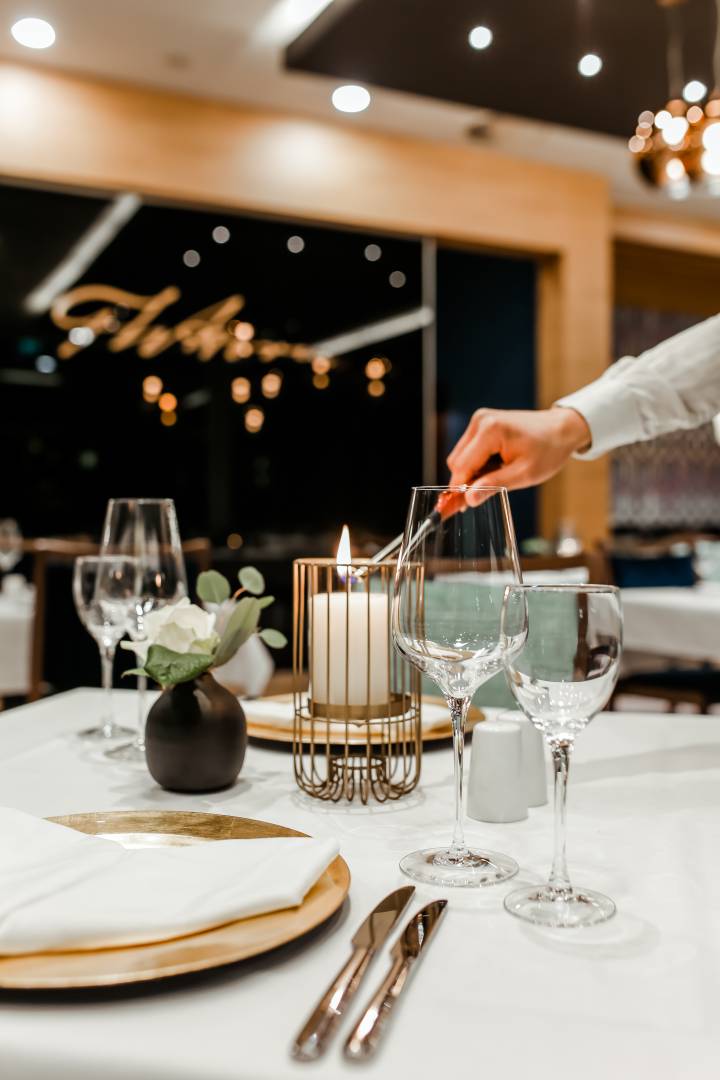 Kellner zündet im Restaurant eine Kerze am Tisch an