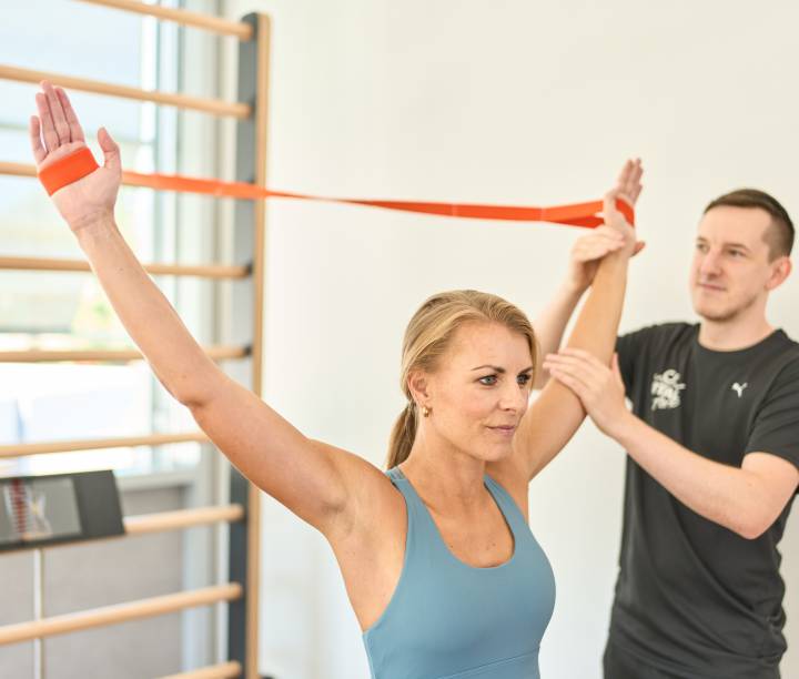 Frau trainiert mit Bändern mit ihrem Personal Trainer