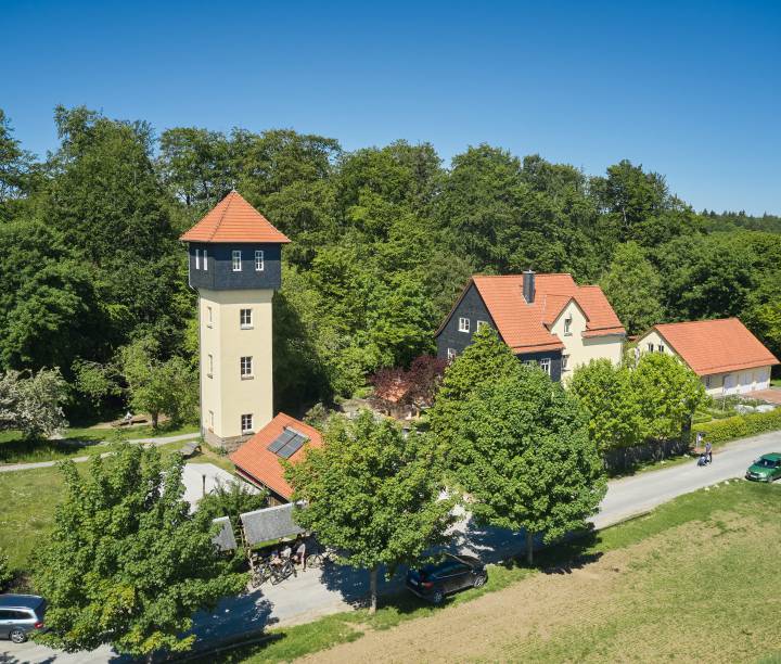 Luftaufnahme des Naturparkzentrums Fürstenhagen im Eichsfeld mit markantem Turm, eingebettet in eine bewaldete Umgebung.
